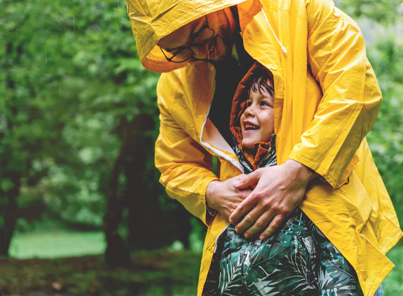 dad shelters child from rain with his coat 